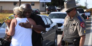 Local resident Jamie Rose (L) is hugged by church member Raymond Antonio as she delivers flowers, at the entrance to the First Baptist Church (back) after a mass shooting that killed 26 people in Sutherland Springs, Texas on November 6, 2017.
A gunman wearing all black armed with an assault rifle opened fire on a small-town Texas church during Sunday morning services, killing 26 people and wounding 20 more in the last mass shooting to shock the United States. / AFP PHOTO / Mark RALSTON        (Photo credit should read MARK RALSTON/AFP/Getty Images)